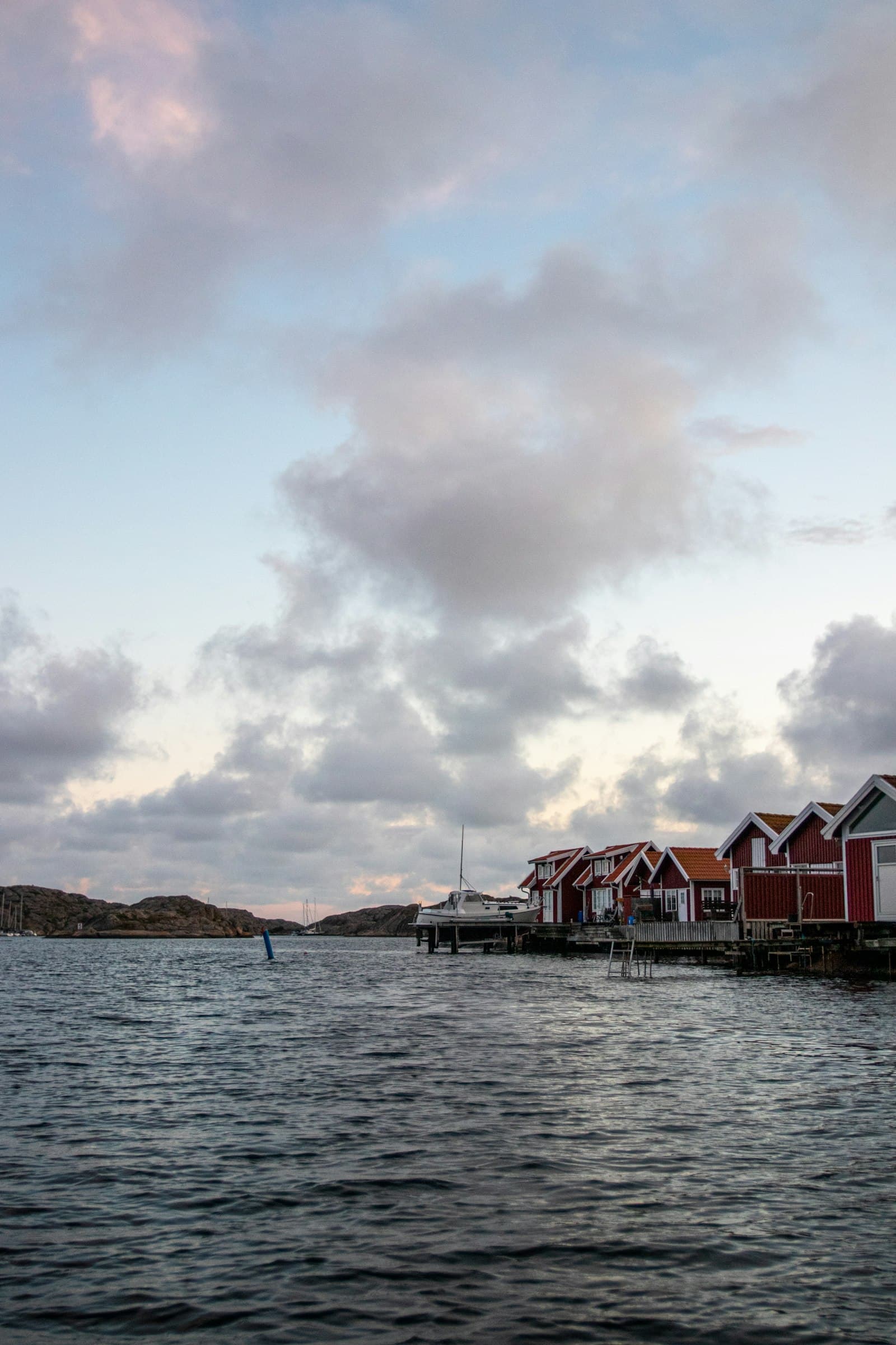 Röda sjöbodar vid en nordisk kust i skymningen